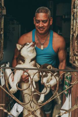 Cuban man smiling with his two huskys